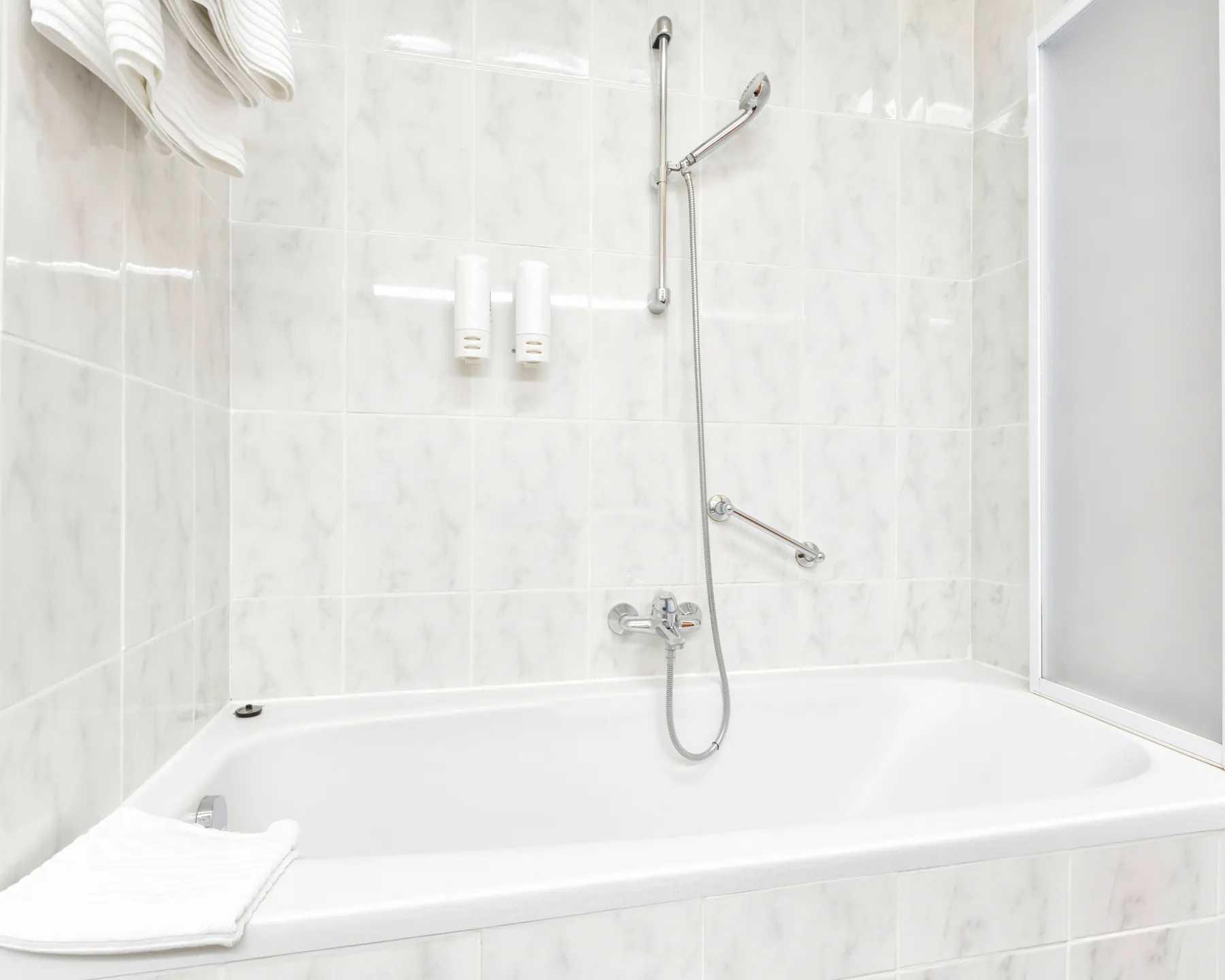 Placeholder image of a bathtub surrounded by light marble-look tile.